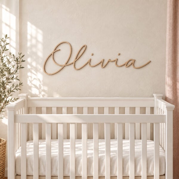 Wooden script nursery name sign reading Olivia in Barewood Natural, mounted on the wall above a white crib.