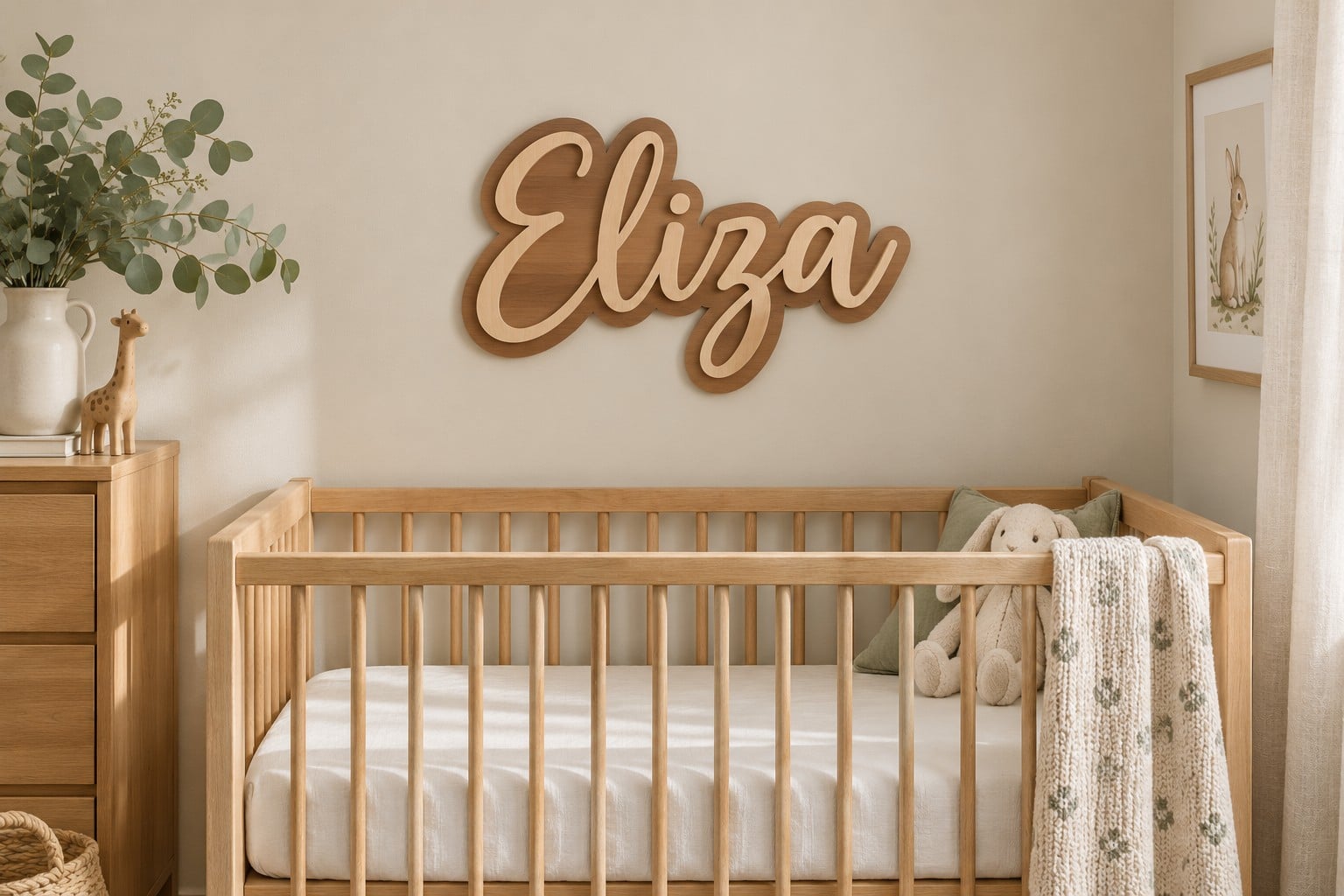 A two-layer wood name sign reading Eliza above a natural wood crib